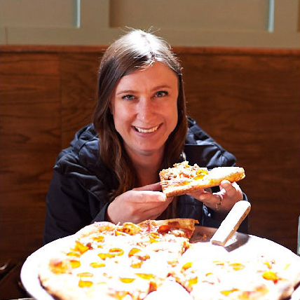 A woman holding a slice of pizza.